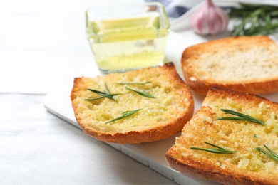 Photo of Slices of toasted bread with garlic and herb on white wooden table, closeup