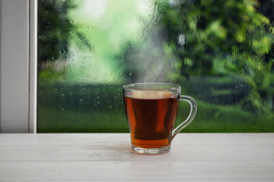 Image of Cup of hot drink near window on rainy day