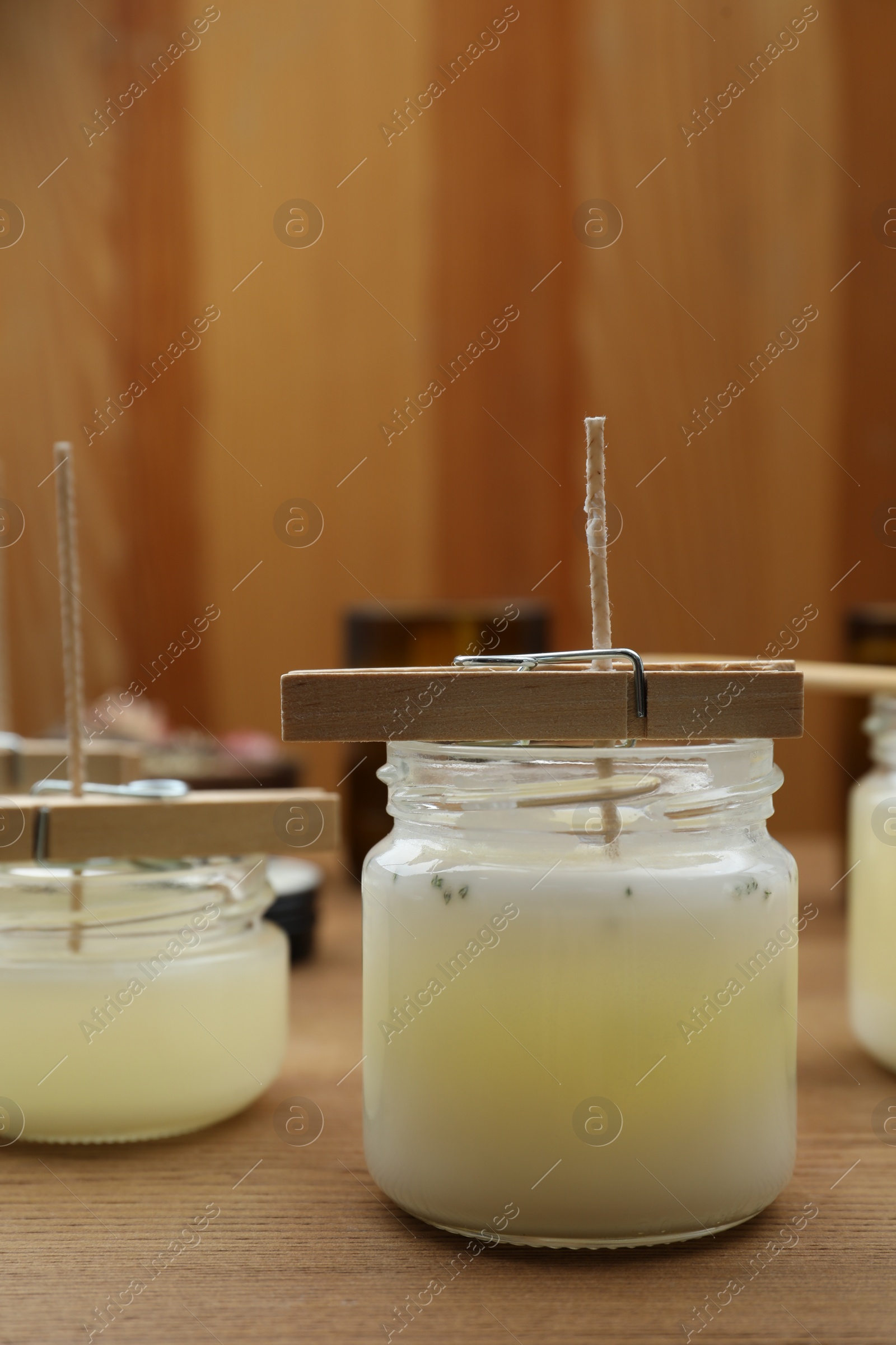 Photo of Glass jars with wax on wooden table. Handmade candles