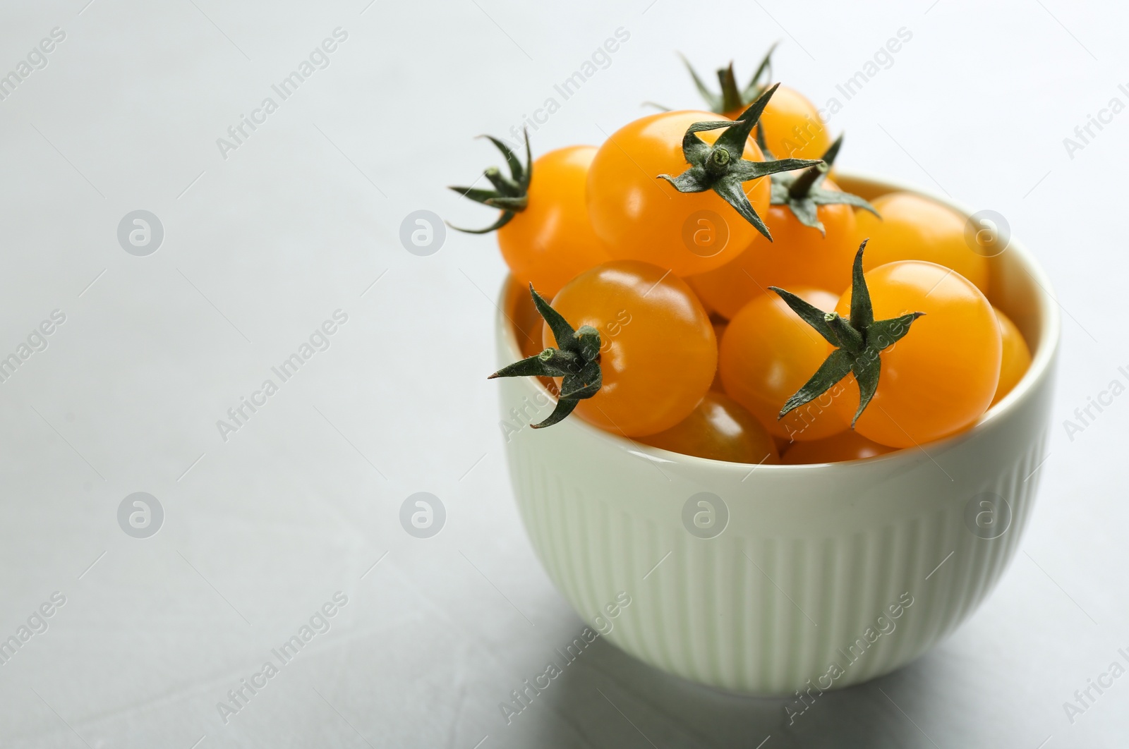 Photo of Ripe yellow tomatoes on grey table. Space for text