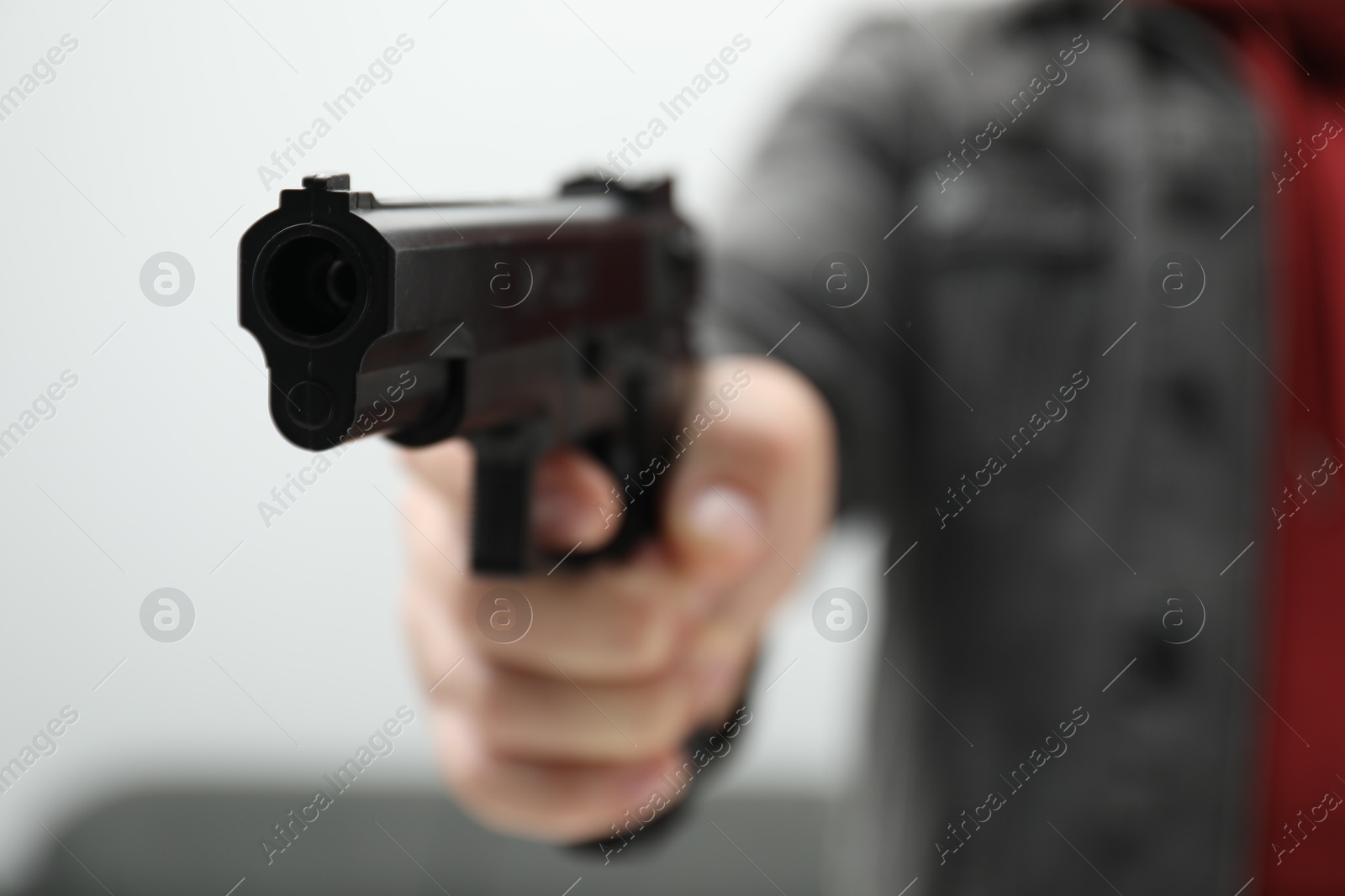 Photo of Dangerous criminal with gun indoors, closeup. Armed robbery