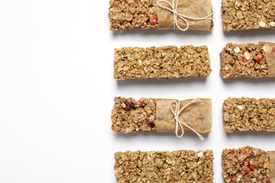 Different tasty granola bars on white background, flat lay. Space for text