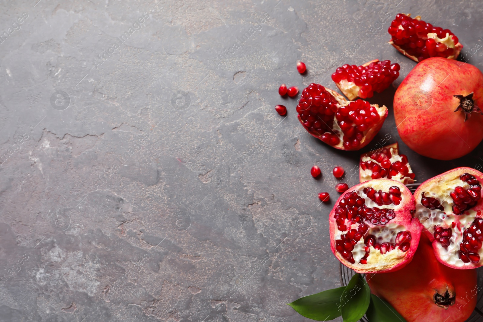 Photo of Flat lay composition with ripe pomegranates and space for text on grey background