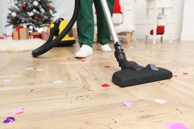 Photo of Woman from cleaning service working in messy room after New Year party, closeup