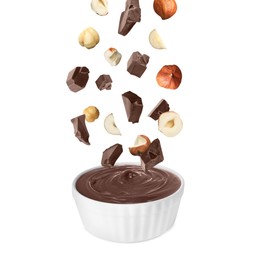 Image of Making yummy chocolate paste. Hazelnuts and pieces of chocolate falling into bowl on white background