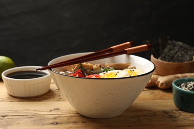 Photo of Bowl of delicious ramen and chopsticks on wooden table. Noodle soup