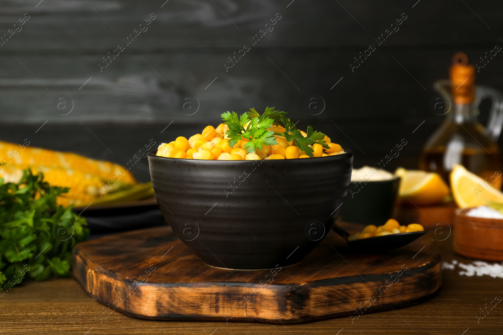 Photo of Bowl with tasty boiled corn on wooden table