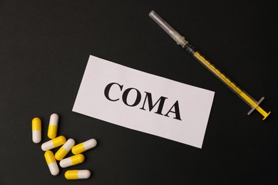 Card with word Coma, syringe and pills on black background, flat lay
