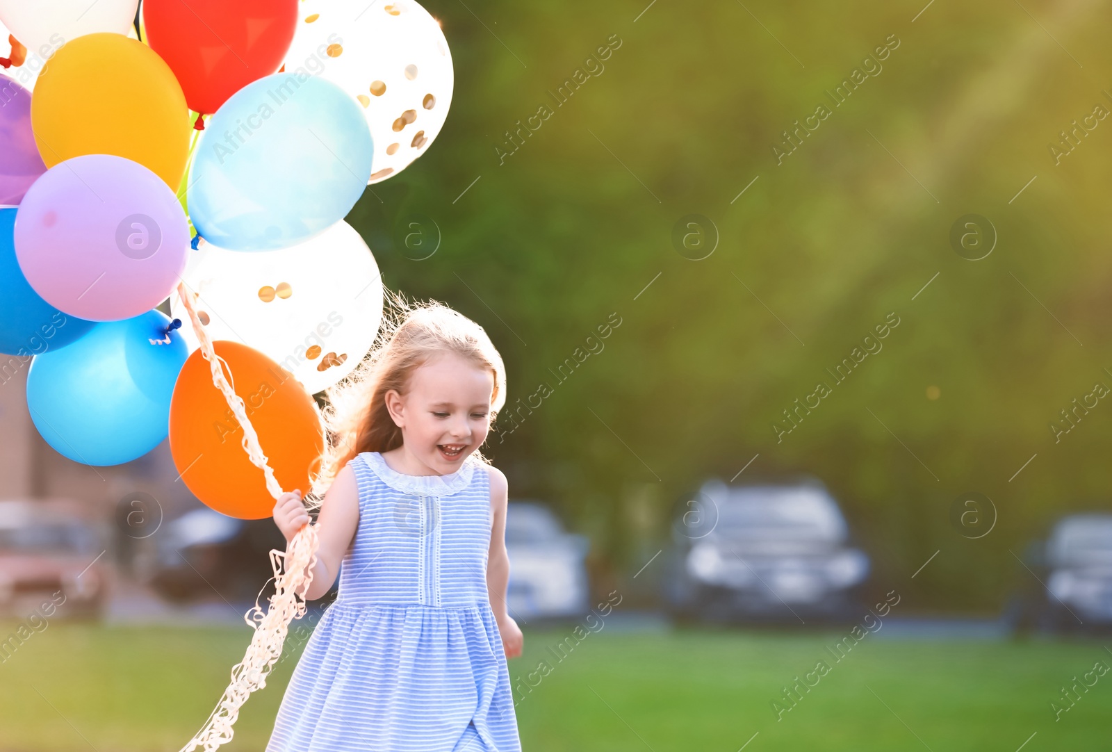 Photo of Little girl with colorful balloons outdoors on sunny day