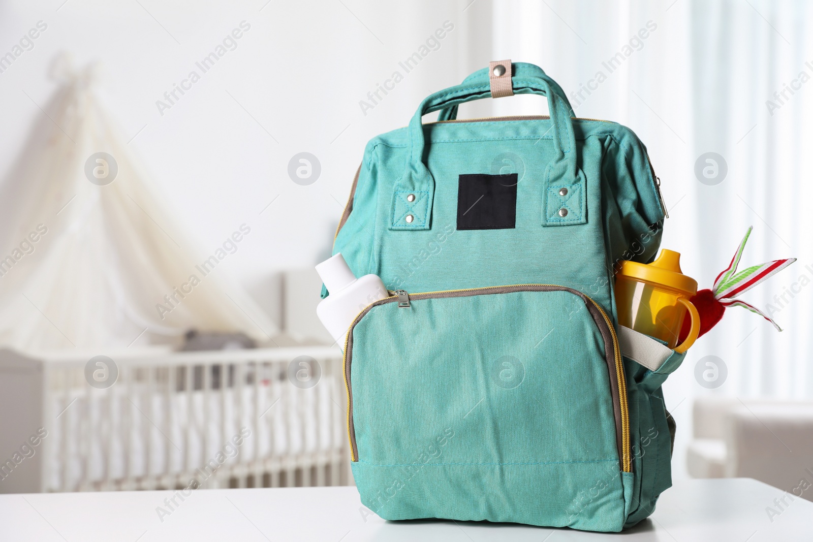 Photo of Maternity backpack with baby accessories on table indoors. Space for text