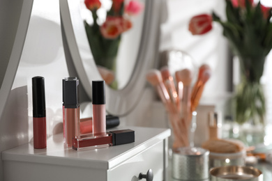 Photo of Different lip glosses on dressing table indoors. Interior element