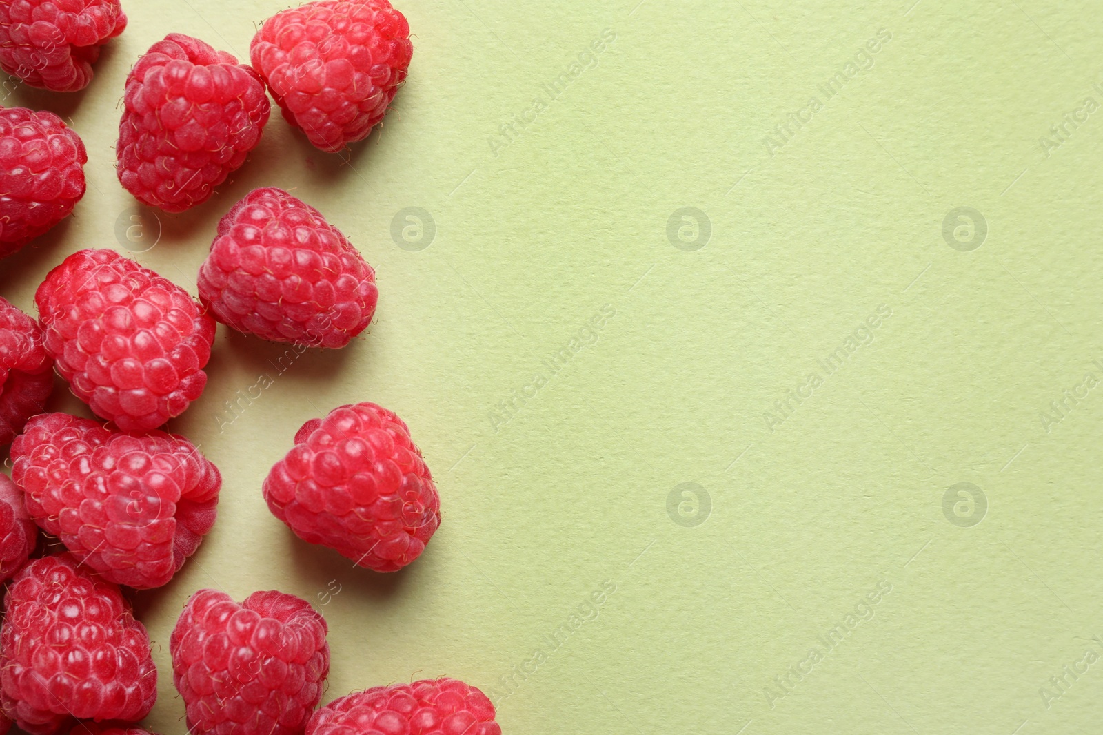 Photo of Fresh sweet ripe raspberries on light green background, flat lay. Space for text