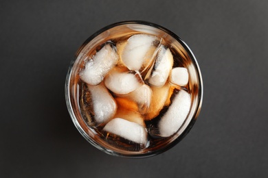 Photo of Glass of tasty refreshing cola with ice cubes on black background, top view