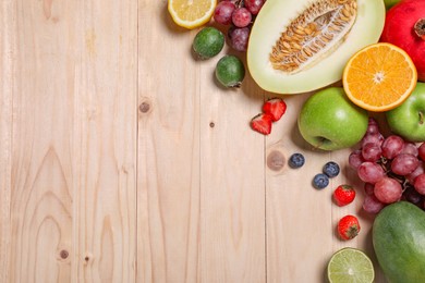 Photo of Many different fresh fruits and berries on wooden table, flat lay. Space for text