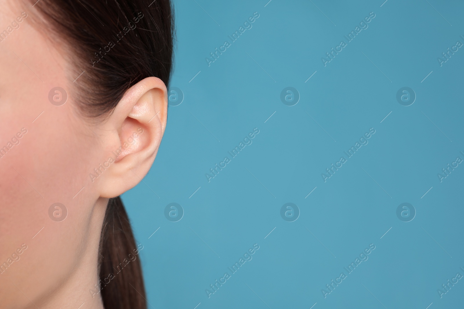 Photo of Woman on light blue background, closeup of ear. Space for text