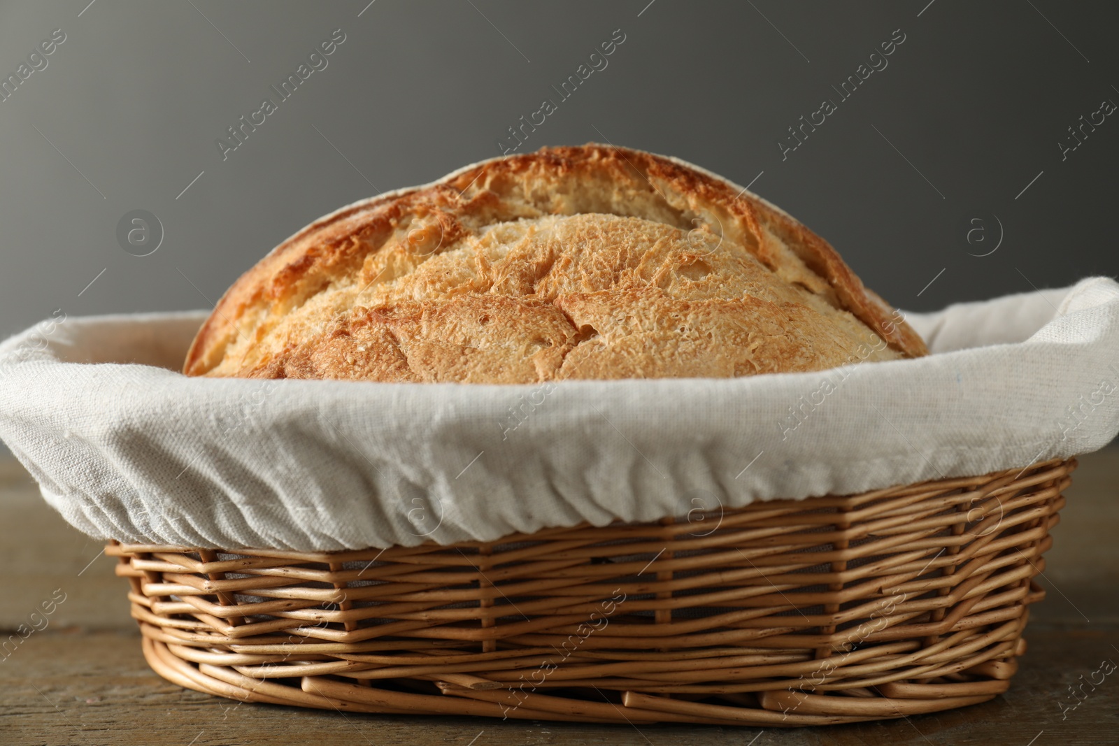 Photo of Wicker basket with fresh bread on wooden table, closeup