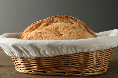 Photo of Wicker basket with fresh bread on wooden table, closeup