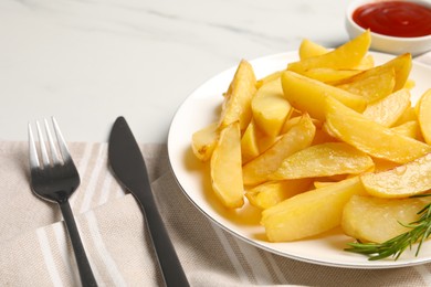 Photo of Plate with tasty baked potato wedges, rosemary and sauce on white table, closeup