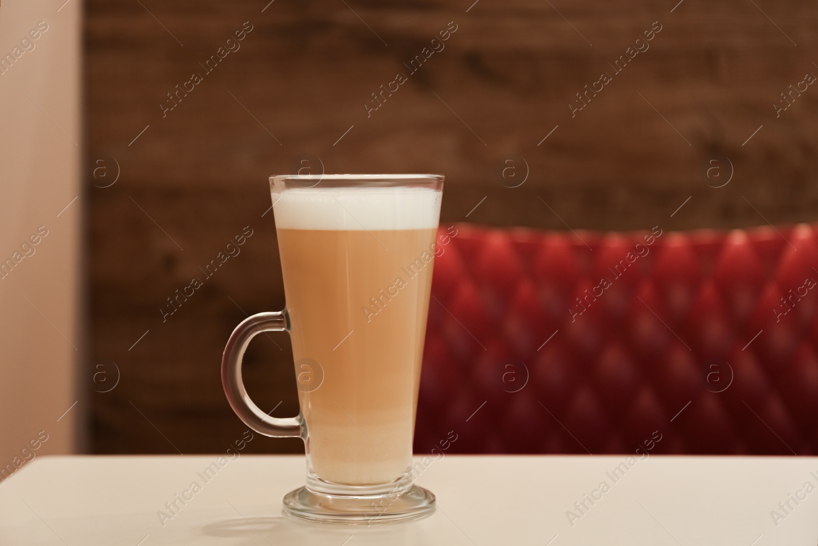 Photo of Glass with delicious coffee on beige table in cafe. Space for text