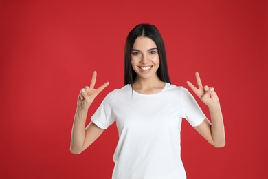 Woman showing number four with her hands on red background