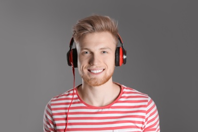 Handsome young man listening to music with headphones on color background