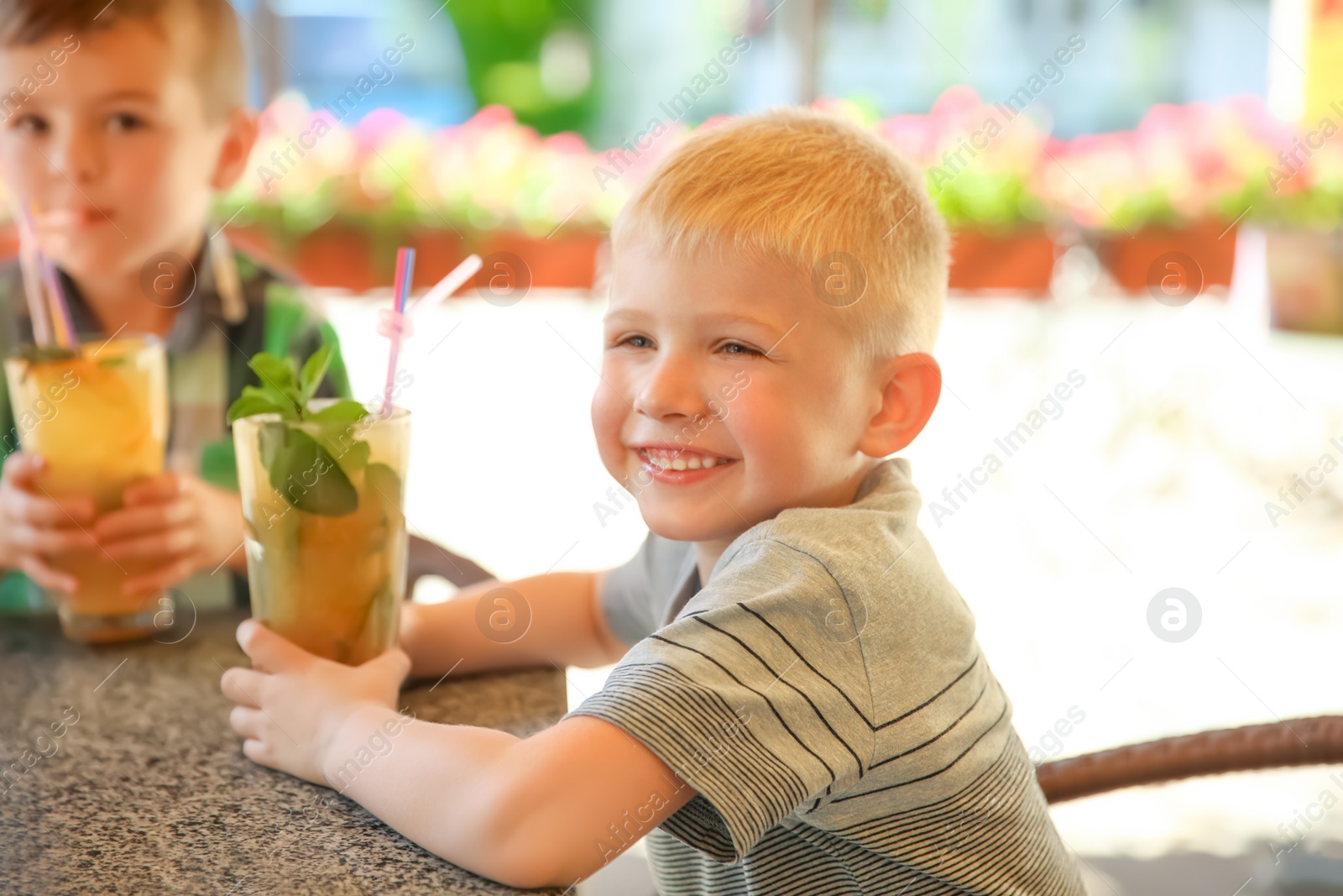 Photo of Cute children with natural lemonade at table in cafe