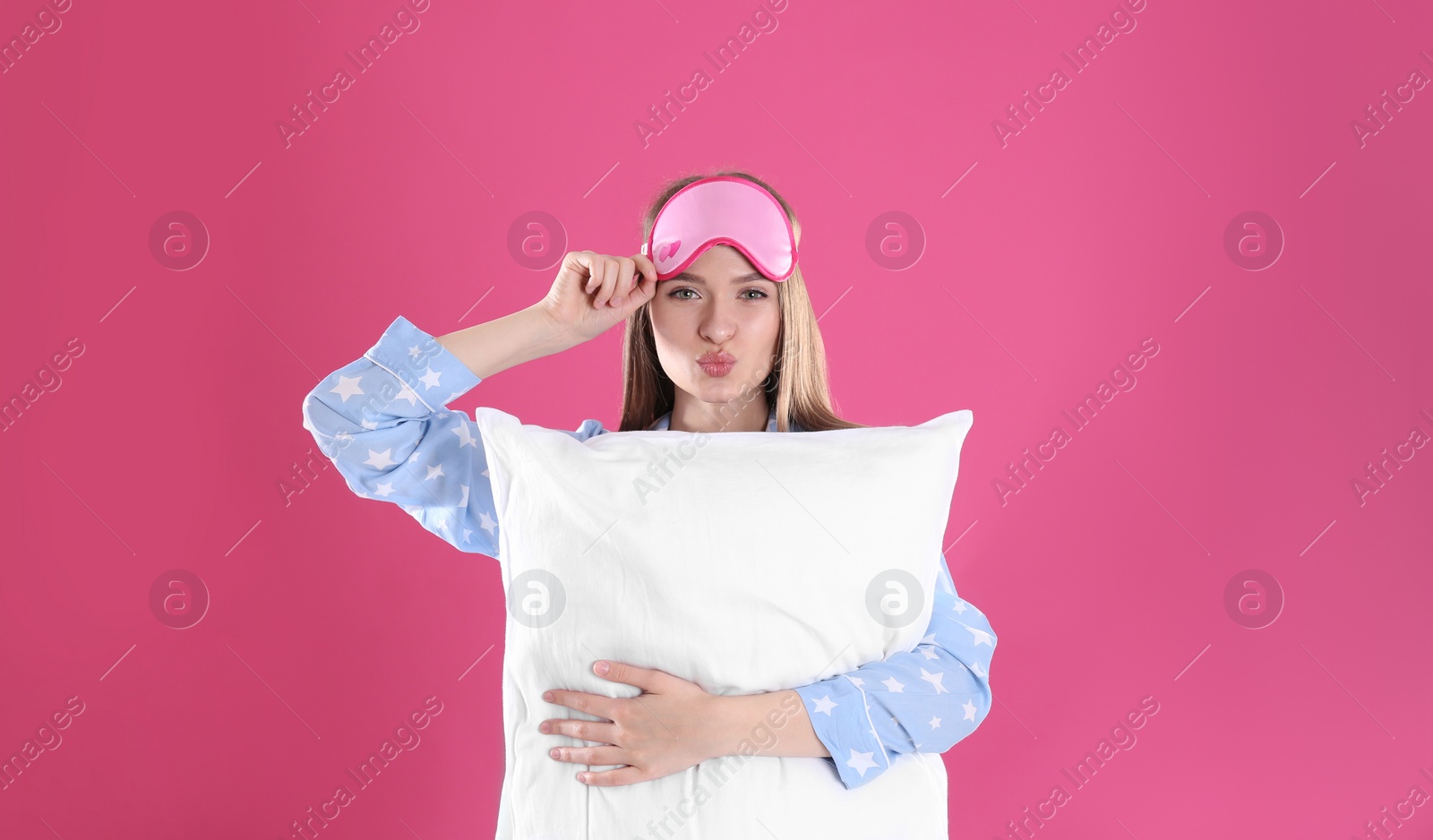 Photo of Young woman with pillow and sleep mask on pink background