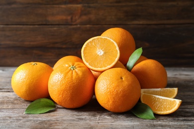 Fresh oranges with leaves on wooden table