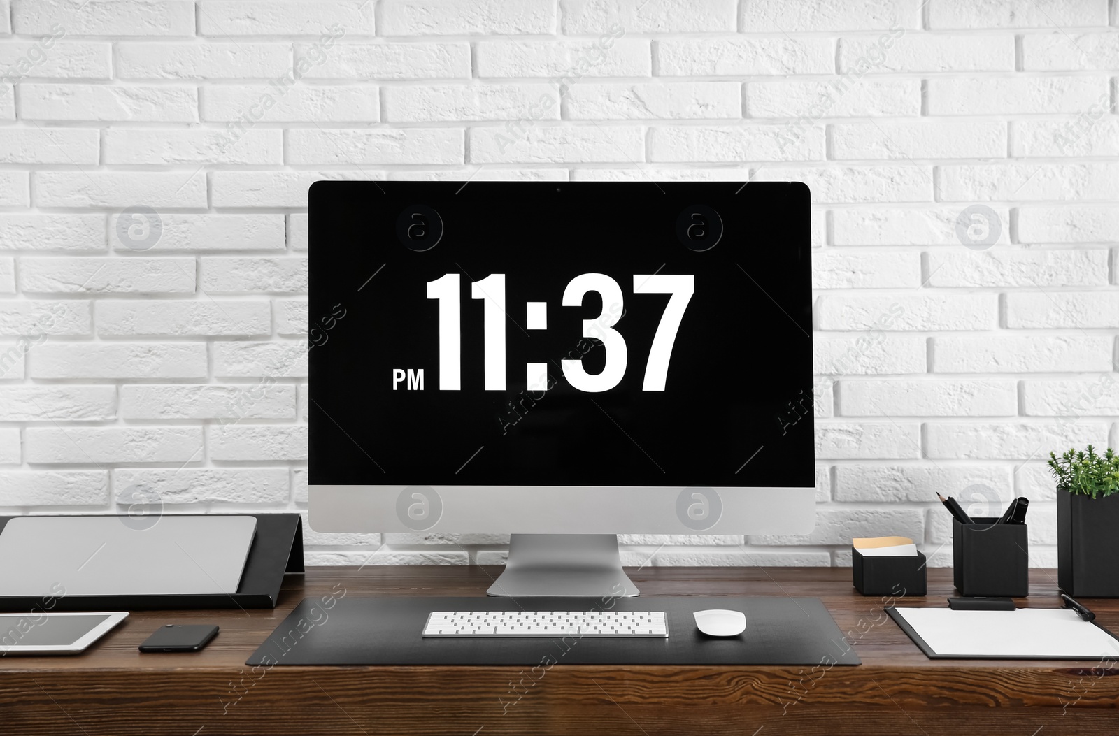 Photo of Modern workplace interior with computer and devices on table near brick wall