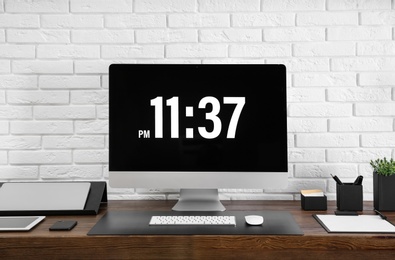 Photo of Modern workplace interior with computer and devices on table near brick wall