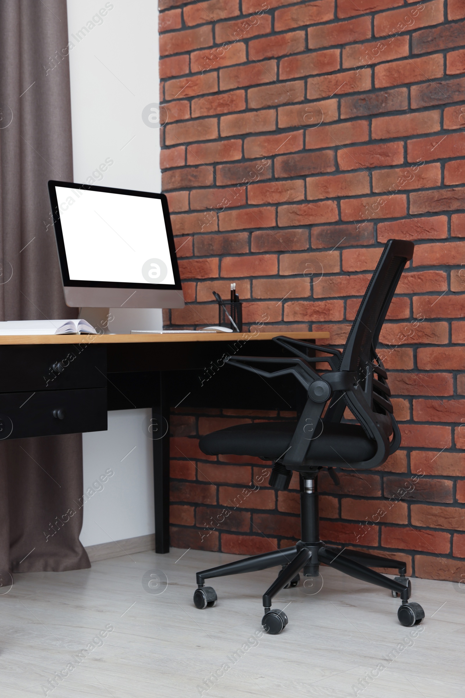 Photo of Stylish office interior with comfortable chair, desk and computer