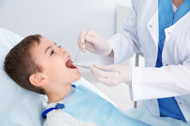 Photo of Dentist examining cute boy's teeth in modern clinic