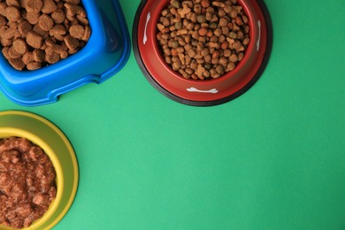 Dry and wet pet food in feeding bowls on green background, flat lay. Space for text