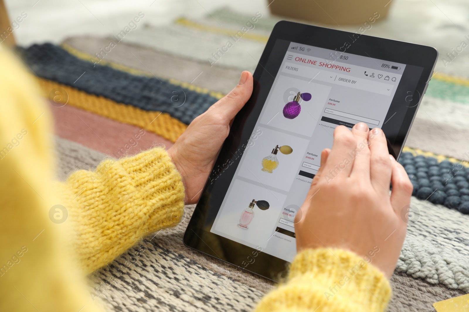 Photo of Woman using tablet for online shopping on carpet, closeup