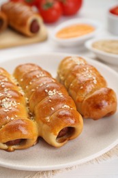 Delicious sausage rolls and ingredients on white wooden table, closeup