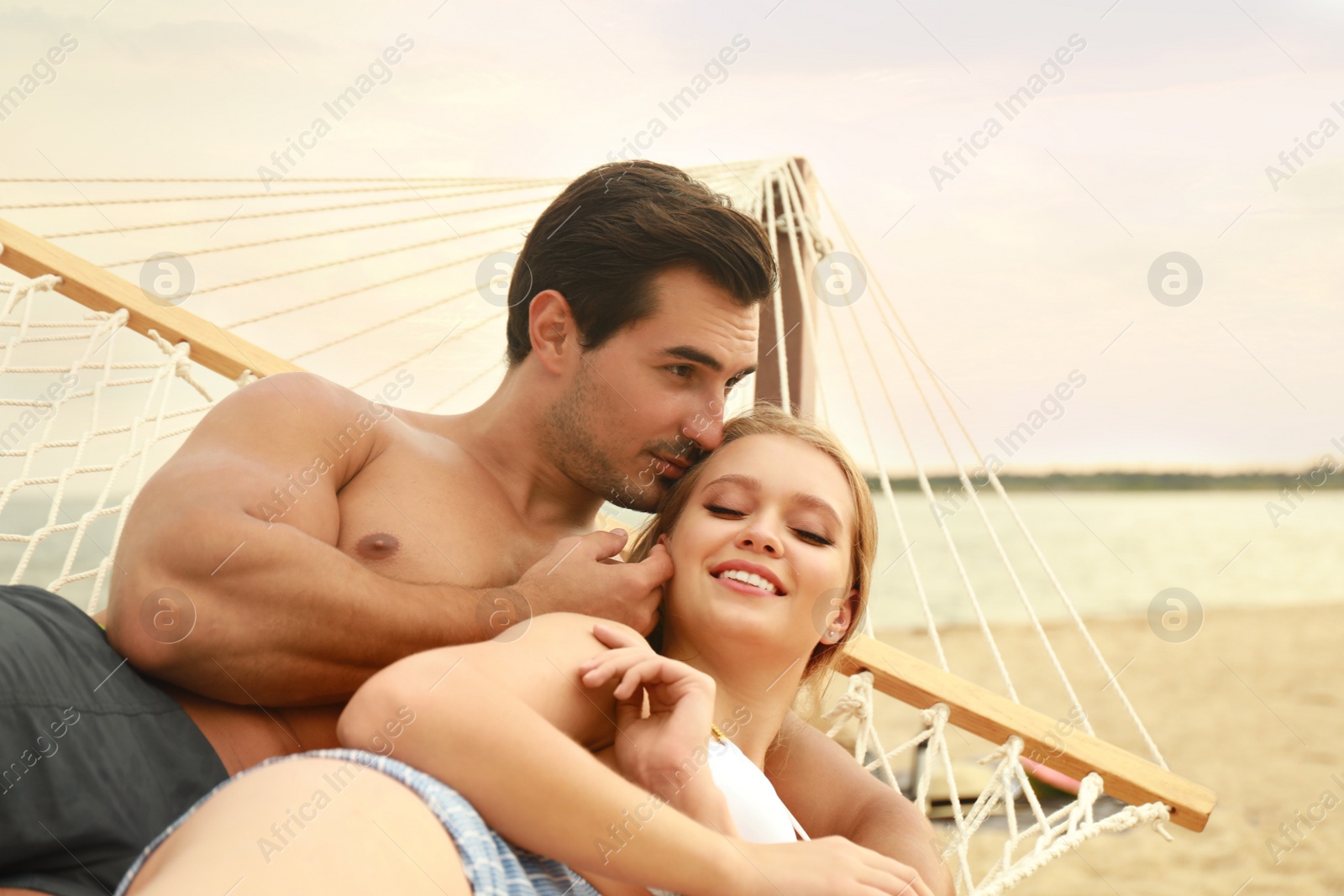 Photo of Beautiful young couple resting in hammock at sea beach