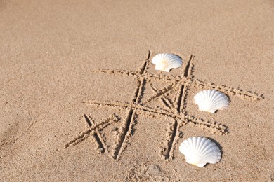 Photo of Playing Tic tac toe game with shells on sand. Space for text