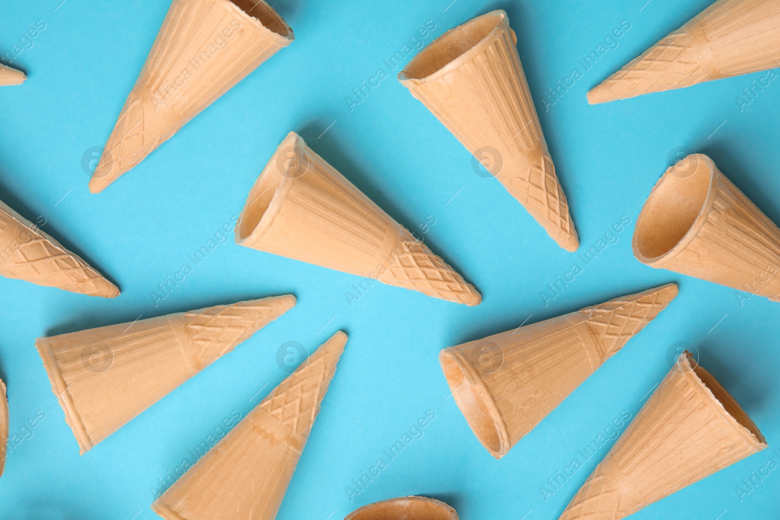 Photo of Waffle empty ice cream cones on color background, flat lay