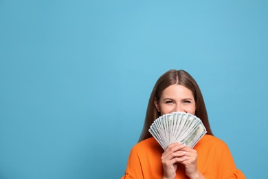 Photo of Portrait of emotional lottery winner with money fan on light blue background, space for text