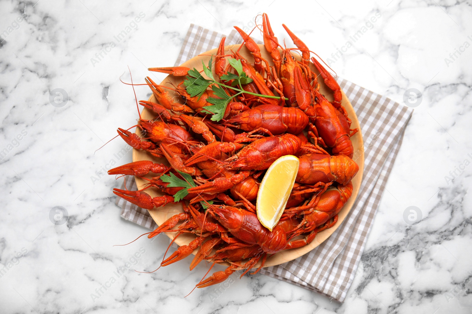 Photo of Delicious boiled crayfishes on white marble table, top view