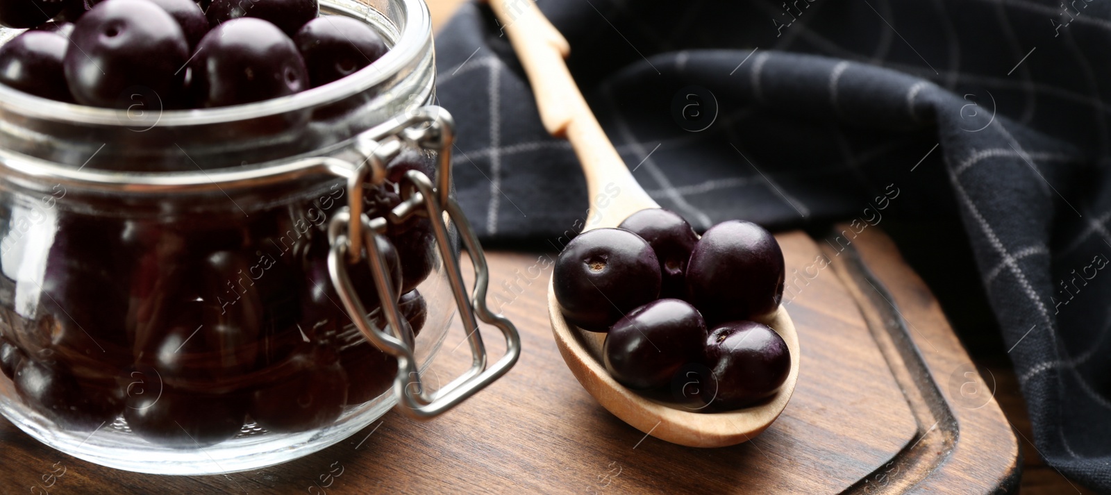 Photo of Jar with fresh acai berries on table, closeup