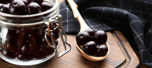 Photo of Jar with fresh acai berries on table, closeup