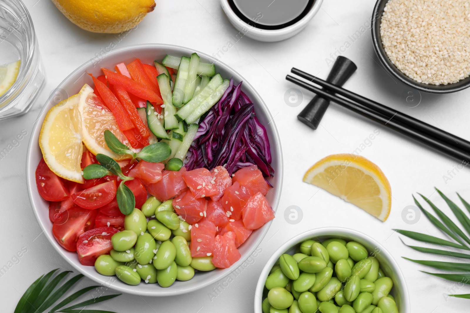 Photo of Poke bowl with salmon, edamame beans and vegetables on white table, flat lay