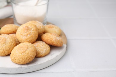 Photo of Tasty sweet sugar cookies and milk on white tiled table, closeup. Space for text