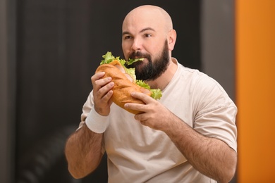 Overweight man eating sandwich in gym