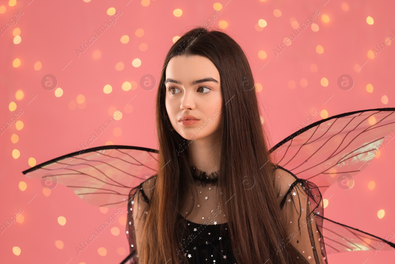 Photo of Beautiful girl in fairy costume with wings on pink background