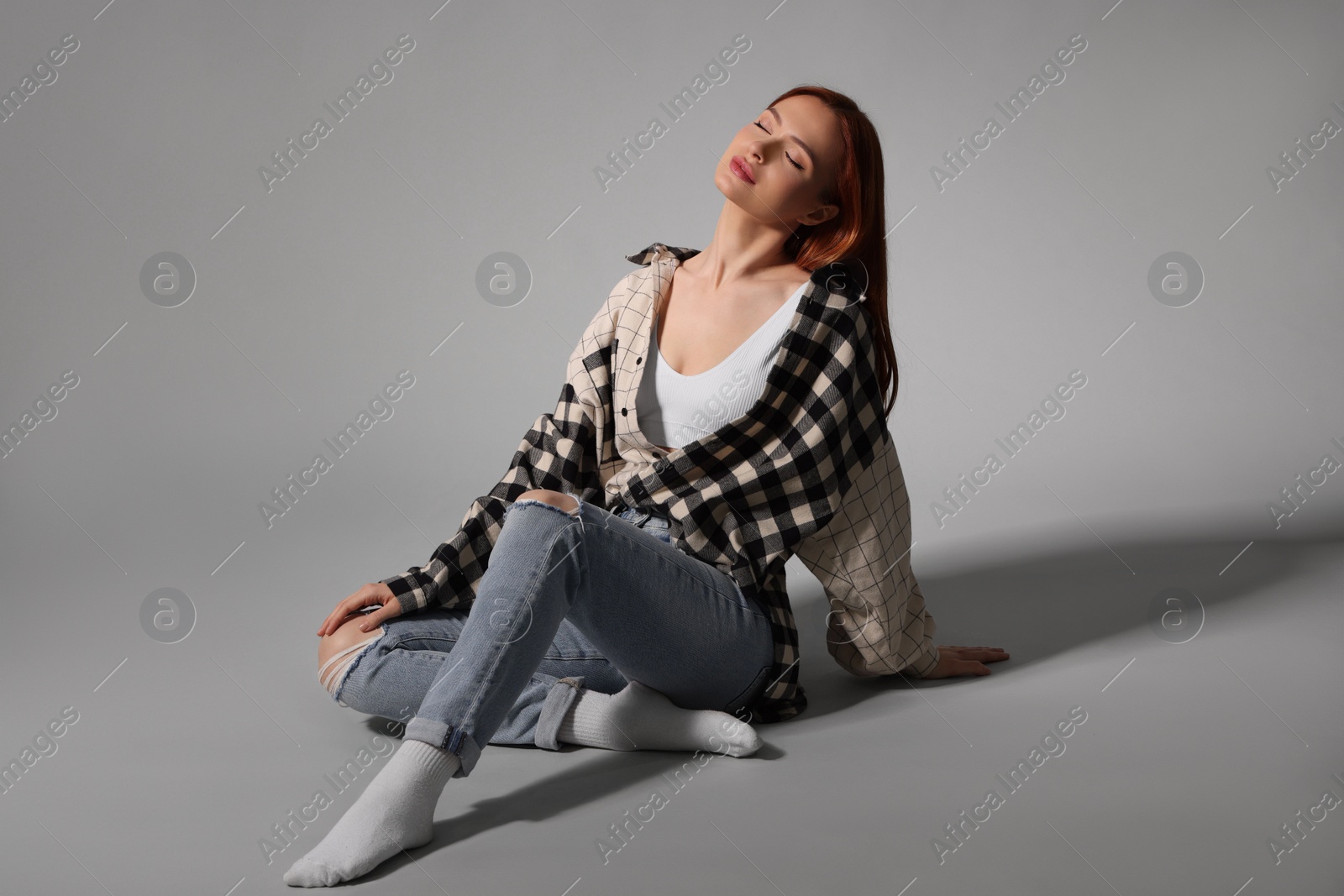 Photo of Beautiful young woman sitting on gray background