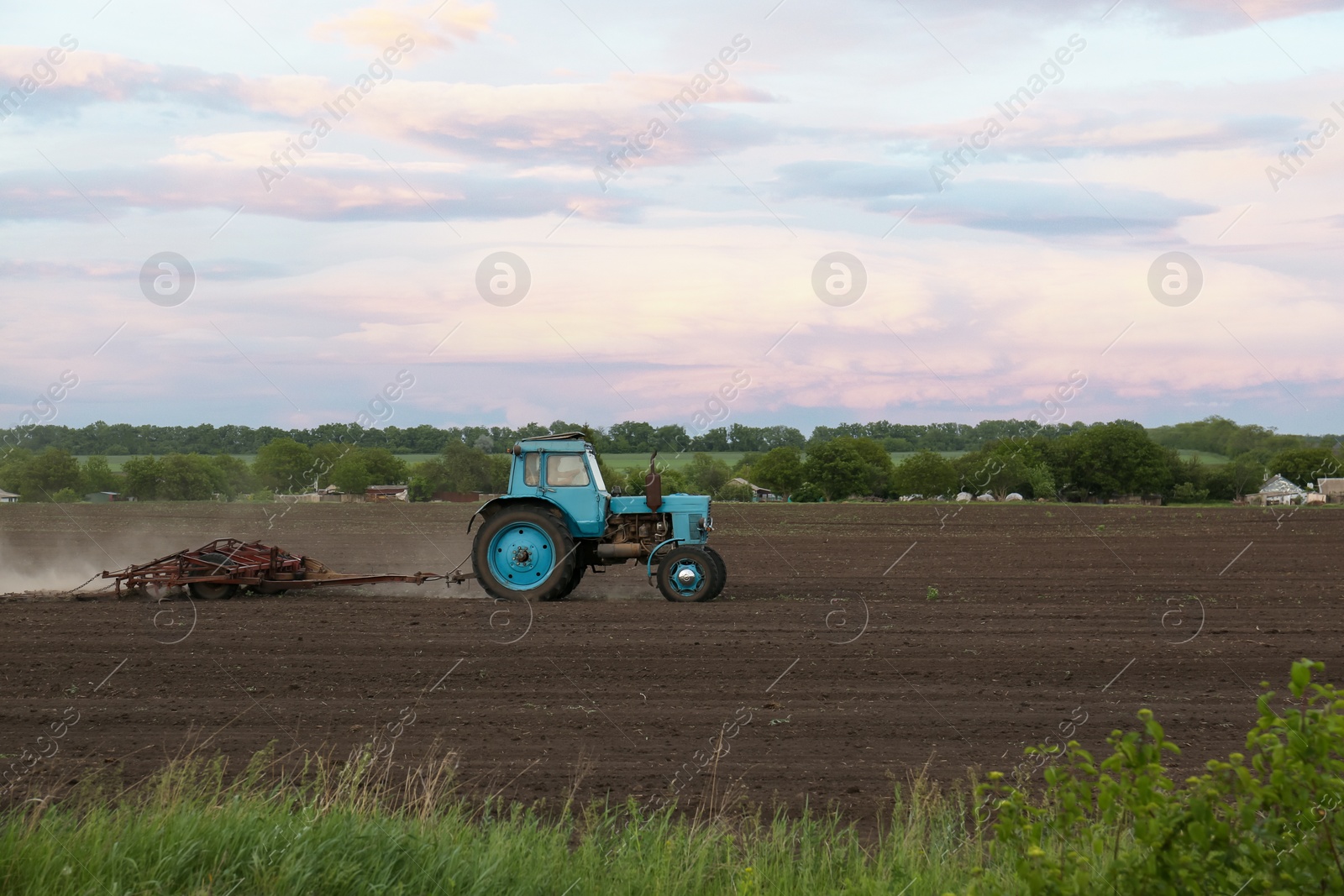 Photo of Tractor plowing agricultural field under cloudy sky