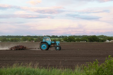 Tractor plowing agricultural field under cloudy sky