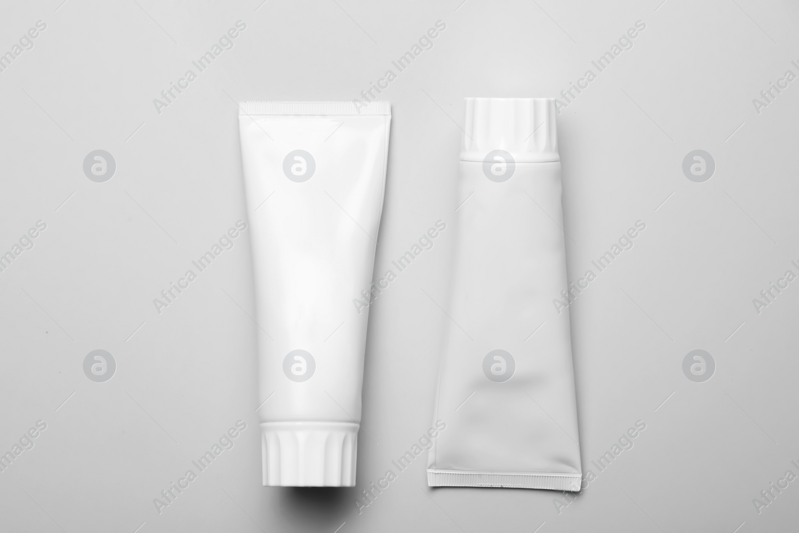 Photo of Blank tubes of toothpaste on white background, top view